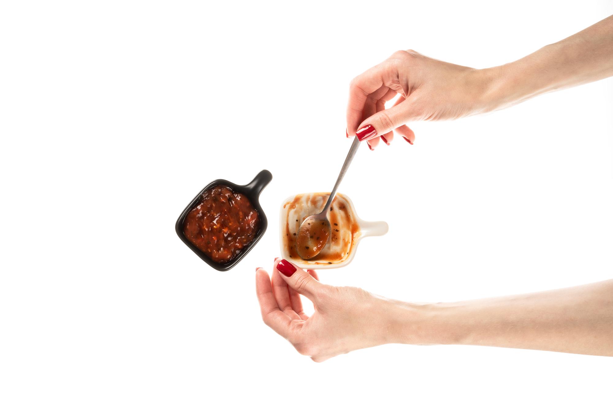hands pouring sauce with precision spoon